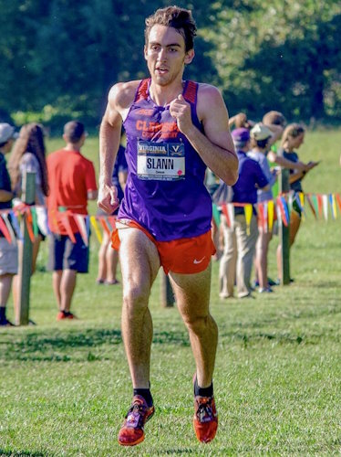 Gift of Life Marrow Registry donor Jacob signed up to become a volunteer blood stem cell/marrow donor while a student at Clemson University, where he was on both the cross country and track teams. He is shown here running on grass during a cross-country meet and is wearing the purple and orange team uniform of Clemson. 