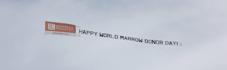 A close up of the aerial banner that was flown over South Florida beaches for World Marrow Donor Day. The front of the banner shows the orange Gift of Life logo with the website url, and the wording of the banner itself says "Happy World Marrow Donor Day!" 