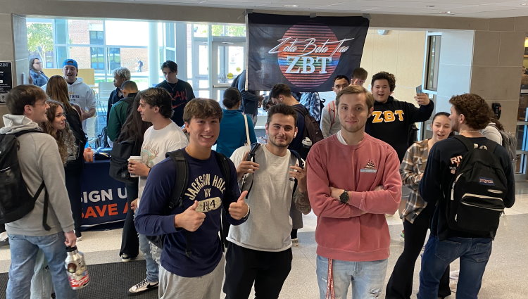 Students crowd around a table to swab their cheeks as ZBT brothers run an on-campus donor recruitment drive for Gift of Life Marrow Registry.