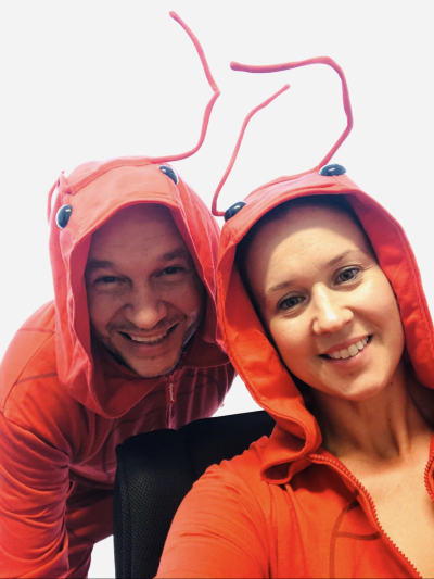 Ignacio and wife Melissa are smiling into the camera while dressed as lobsters in red hoodies with eyes and antenna e attached to the hoods.  
