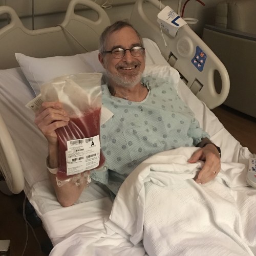 Stem cell transplant recipient Paul Kaplowitz holding up the lifesaving, donated stem cells before his infusion begins. 