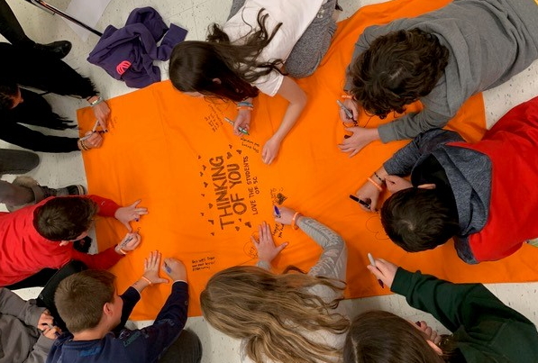 The fourth grade class signs a blanket to send to Jarred's recipient.