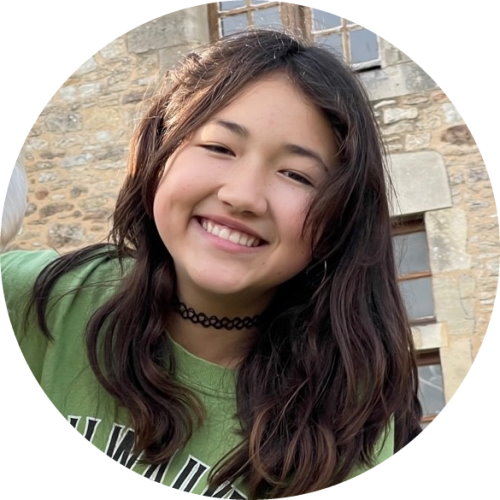 Gift of Life is helping 13-year-old Maxine search for her donor to fight Severe Aplastic Anemia. She is half Korean and half French, and in this photo she is wearing a bright green shirt and smiling at the camera.