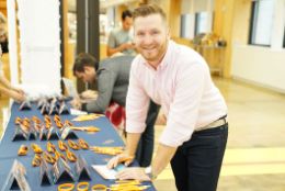 At a "Swab at Your Job" event, people are signing up to join Gift of Life Marrow Registry at a table covered in swab kits and pens.