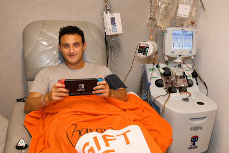 At Gift of Life's Adelson Collection Center, a donor is in the collection center playing a video game while he donates stem cells.