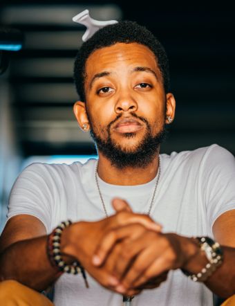 Rapper Terrell "Trizzy" Myles is shown in this photo. He is a young, Black man and has a short beard. He is sitting down with his hands grasped in front of him. Terrell created the award-winning "Blood is Thicker" video for Gift of Life.